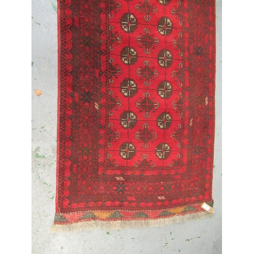 26 - Afghan runner with two rows of gols on a red ground with borders, 9ft 6ins x 2ft 10ins approximately