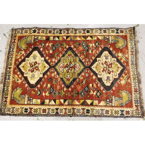 32 - Kurdish rug with a triple pole medallion design on rose ground, with all over further stylised bird ... 