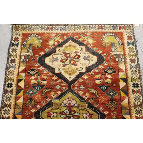 32 - Kurdish rug with a triple pole medallion design on rose ground, with all over further stylised bird ... 