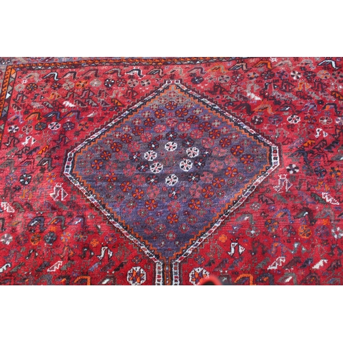 5 - Shiraz carpet with a triple pole medallion and all-over stylised design on a red ground with multipl... 