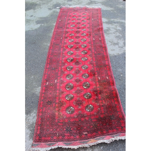 21 - Afghan runner with two rows of gols on a red ground with borders, 9ft 6ins x 2ft 10ins approximately