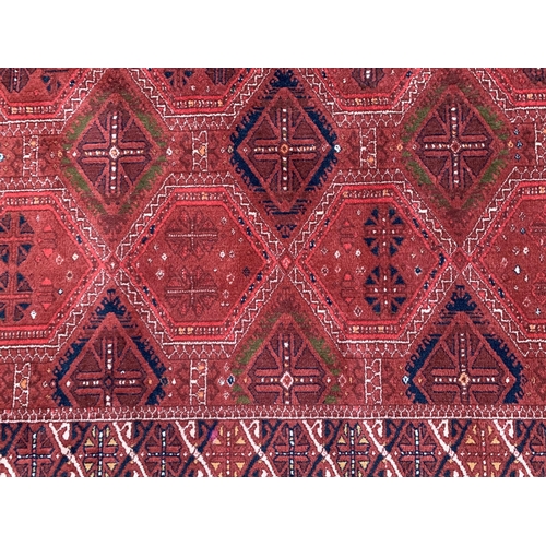 32 - Large good quality machine woven carpet of Turkoman design with multiple rows of gols on a wine red ... 