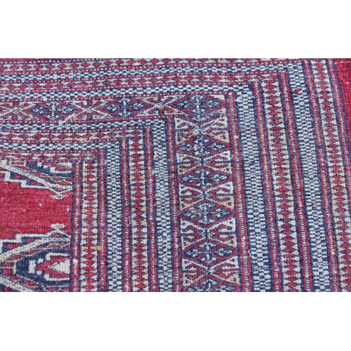 6 - Pakistan rug of Turkoman design with single row of twelve gols on a wine ground with multiple border... 