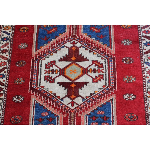13 - Kurdish rug with a quadruple pole medallion design in shades of red and blue with a triple border, 9... 