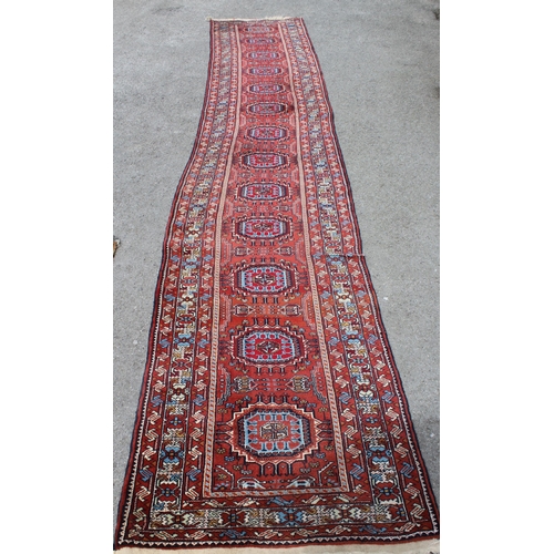 21 - Indo Persian runner of Afghan design with a repeating hooked medallion pattern, on a rose ground wit... 