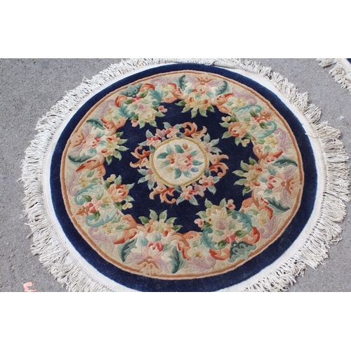 23 - Two similar floral decorated circular Chinese rugs on blue ground (at fault)