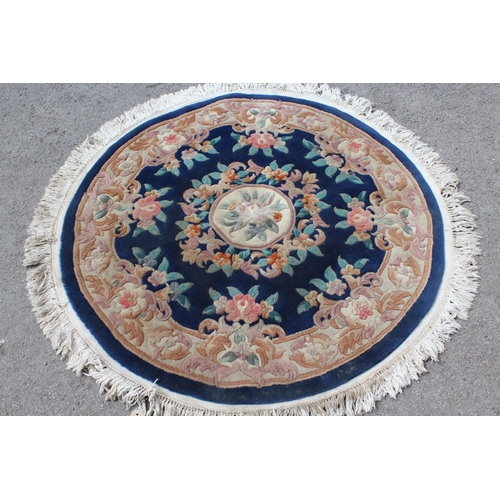 23 - Two similar floral decorated circular Chinese rugs on blue ground (at fault)