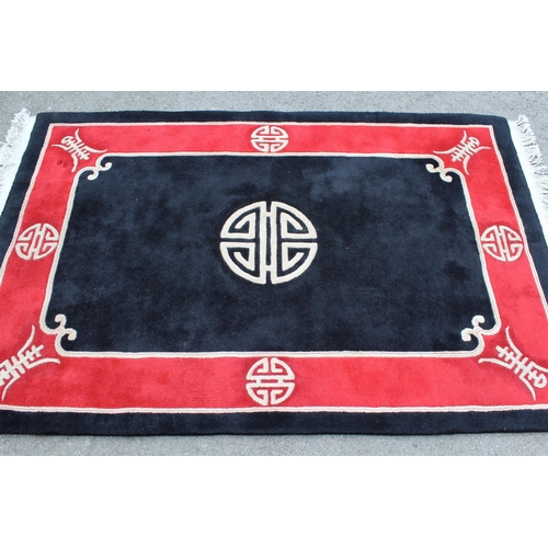 24 - Modern Chinese rug with a circular centre medallion on a black ground with red border, 6ft x 4ft app... 