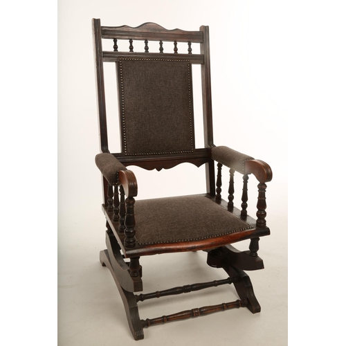 23 - An early 20th century walnut framed American style rocking chair; recently upholstered in grey fabri... 