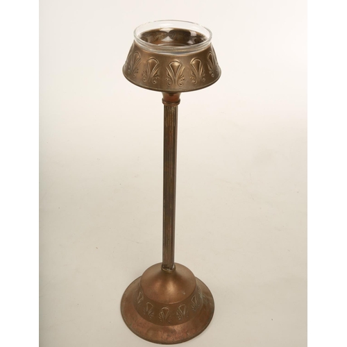 48 - An Art Nouveau embossed brass floor standing smokers stand embossed with stylised flowers; raised on... 