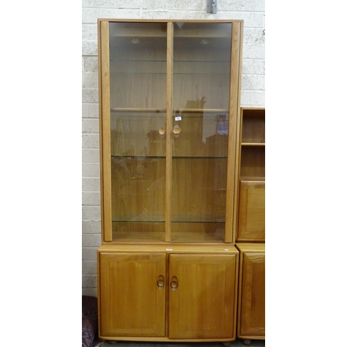 39 - A modern Ercol light elm display cabinet, the upper section fitted with a pair of glazed doors and a... 
