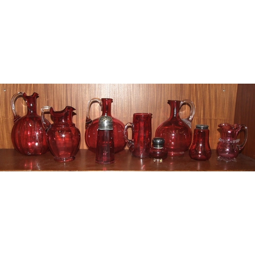 59 - A cranberry glass sugar sifter, 14.5cm high, two jugs and six other pieces of cranberry glass, (9).... 