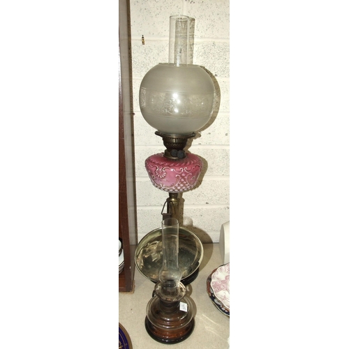 62 - A late-Victorian oil lamp, the pink opaque glass reservoir with painted enamel floral decoration, on... 