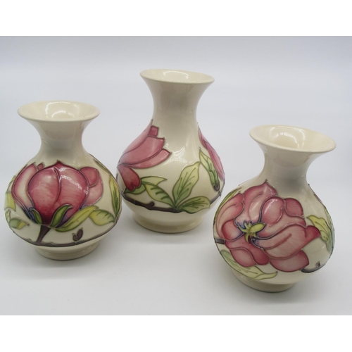 694 - Garniture of three Moorcroft baluster vases decorated pink foliage and branch work on an ivory groun... 