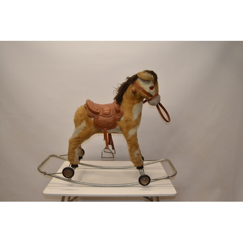 216 - Small child's fur lined rocking horse with plastic saddle, reins and hinged wheels, L90cm W40cm H74c... 