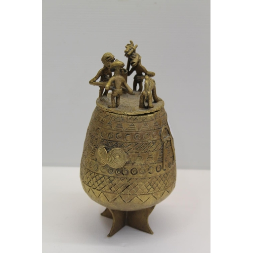 54 - African cast metal jar and cover decorated with geometric design and figures to the lid, 19cm.