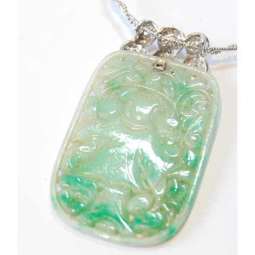 22 - Jadeite pendant, rounded rectangular, with pierced and carved figure and sprays, upon diamond-set wh... 