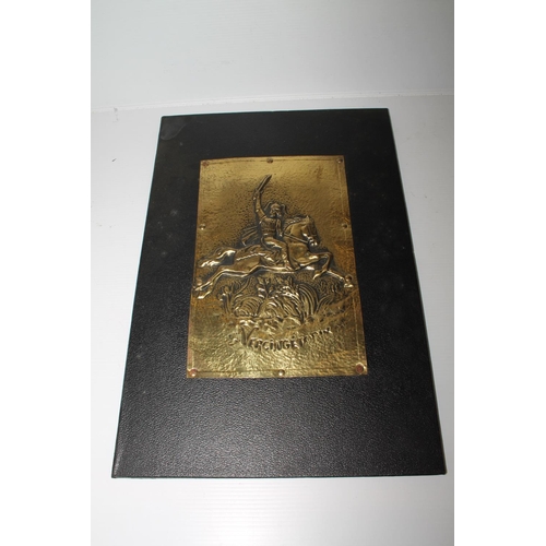 22 - Leather folder decorated with brass repousse plaque depicting warrior on horseback, 36cm.