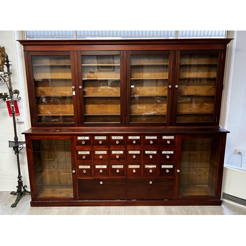1048 - Rare Chemist two height shop cabinet, four sliding glazed doors over a two glazed door base with cen... 
