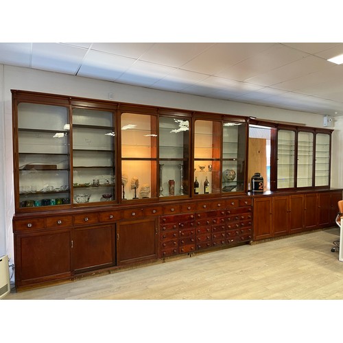 1050 - Long chemist shop cabinet, fitted with nine glazed display top sections, over a multi drawer base (n... 