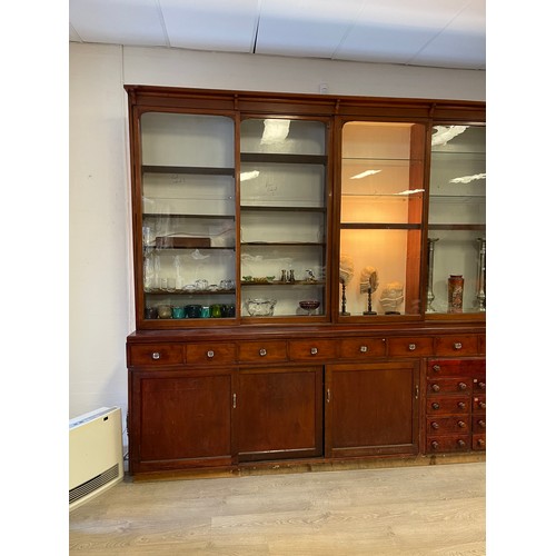 1050 - Long chemist shop cabinet, fitted with nine glazed display top sections, over a multi drawer base (n... 